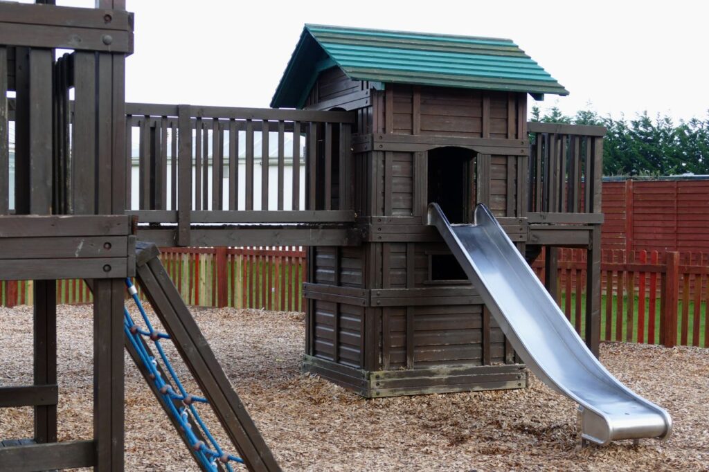 A wooden playground structure with a slide in an outdoor park, ideal for children.